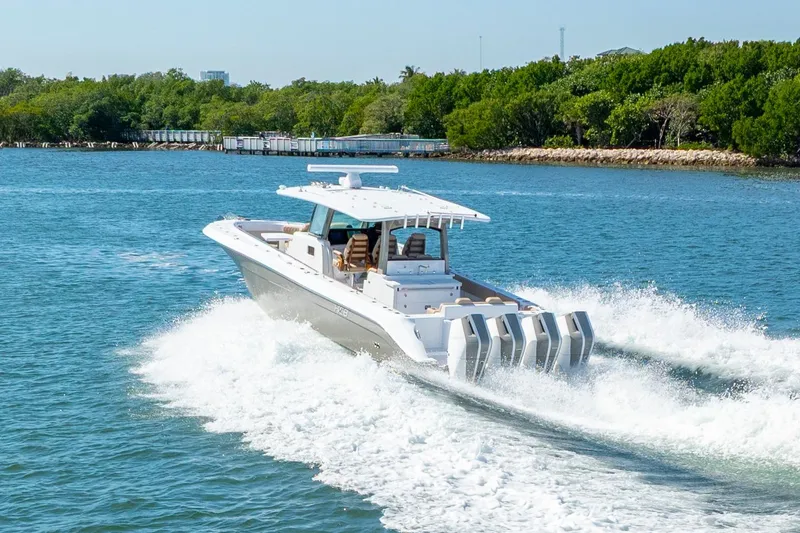 Slide: The Image of 2027 HCB 42 Lujo boat cruising on a sunny day, surrounded by lush greenery. - 30