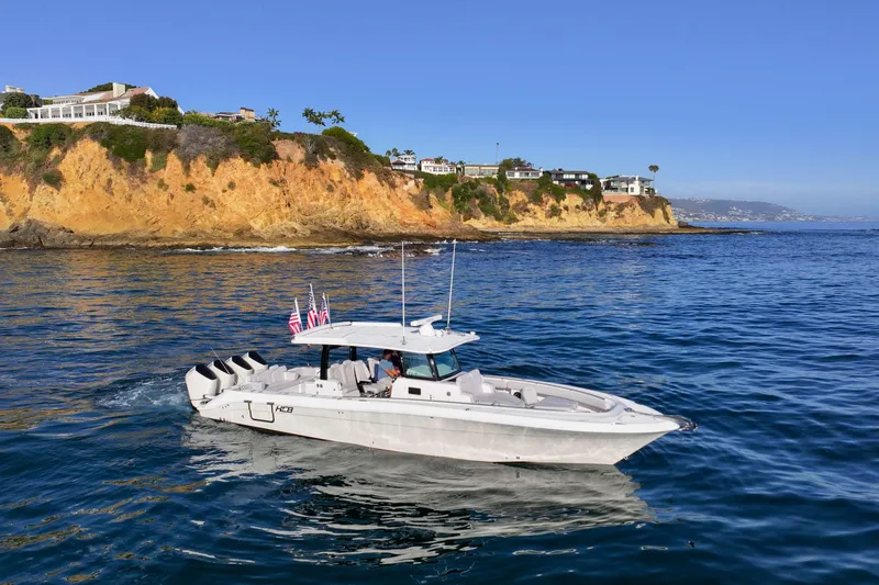 Slide: The Image of 2026 HCB 42 Lujo boat cruising near scenic coastal cliffs. - 6
