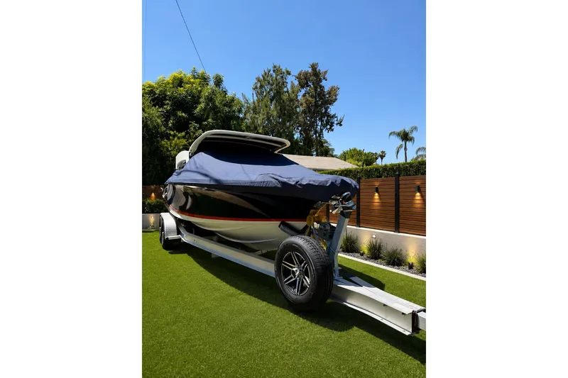 Slide: The Image of 2022 Chris-Craft Launch 25 GT boat on trailer, covered, in a landscaped yard. - 7