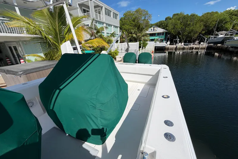 Slide: The Image of 2007 Contender 33 Tournament boat docked by waterfront homes, featuring green covers and tropical scenery. - 22
