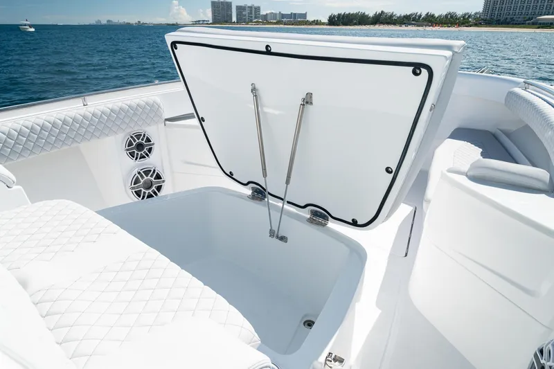 Slide: The Image of 2027 HCB 39 Speciale boat interior with open storage compartment, quilted seating, and ocean view. - 30