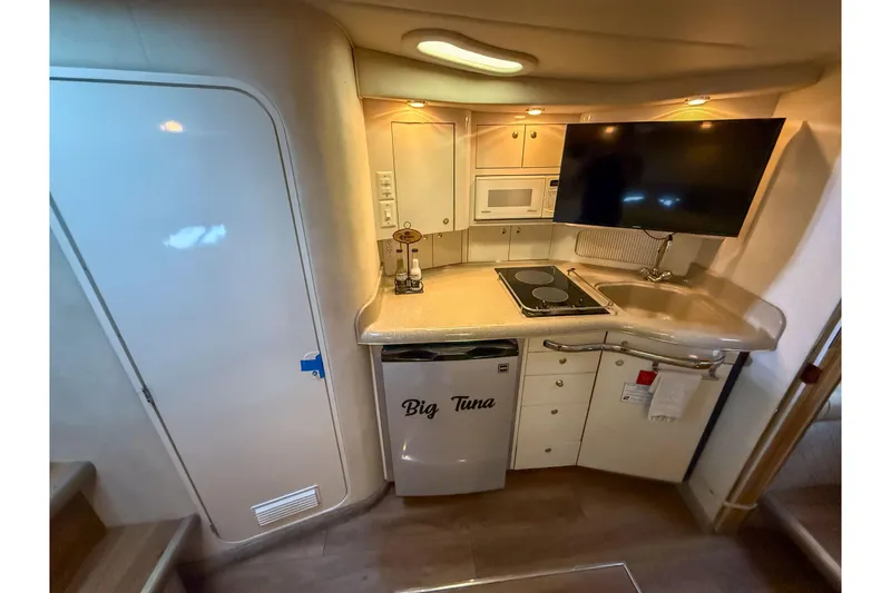Slide: The Image of 1997 Sea Ray 330 Express Cruiser kitchen with stove, sink, fridge, and TV. - 19