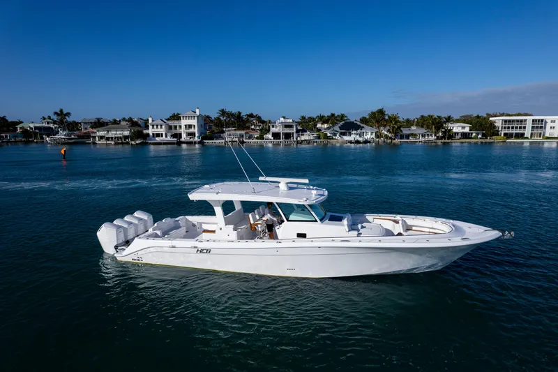 The Image of 2027 HCB 48 Campeon boat cruising on a serene waterfront with luxury homes. - 0