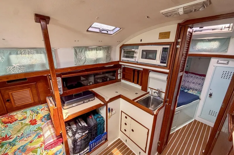 Slide: The Image of Interior of a 1987 Nonsuch 30 Ultra sailboat with compact kitchen and cozy sleeping area. - 11