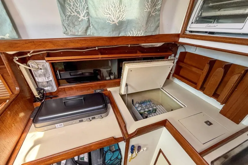 Slide: The Image of 1987 Nonsuch 30 Ultra yacht galley with fridge, grill, and wooden cabinetry. - 12