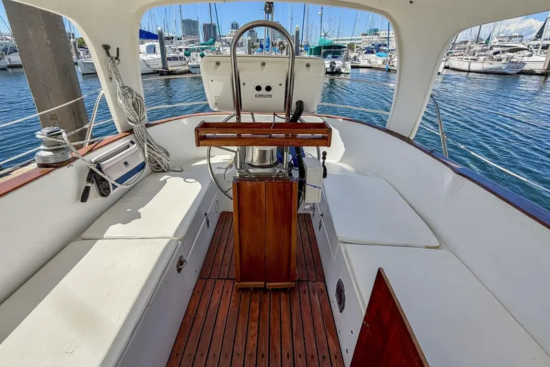 Slide: The Image of 1987 Nonsuch 30 Ultra sailboat cockpit with wooden flooring, marina view, and steering wheel. - 43
