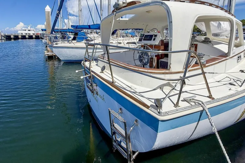 Slide: The Image of 1987 Nonsuch 30 Ultra sailboat docked at marina, featuring spacious cockpit and helm. - 45