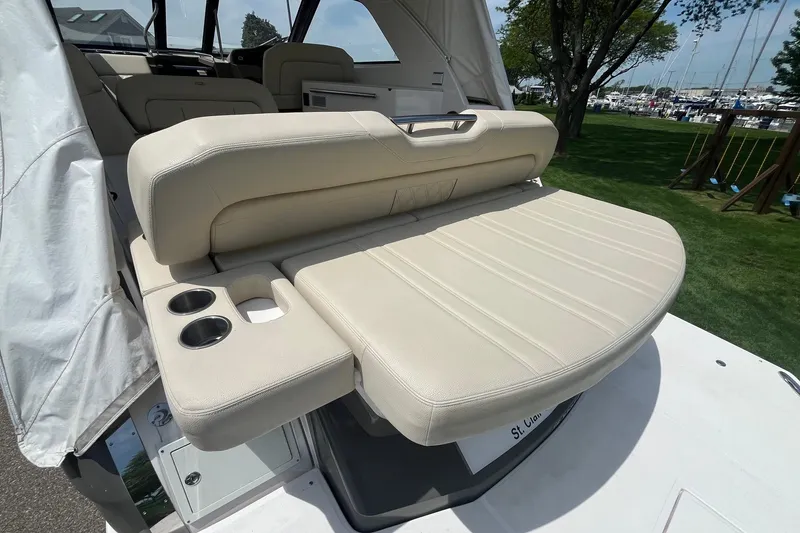Slide: The Image of 2018 Regal 35 Sport Coupe boat with beige seating and cup holders, docked outdoors. - 14