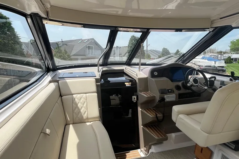 Slide: The Image of Interior of a 2018 Regal 35 Sport Coupe boat with beige seating and modern dashboard. - 24