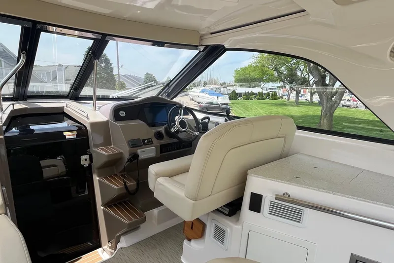 Slide: The Image of Interior of 2018 Regal 35 Sport Coupe, featuring helm and seating area with scenic marina view. - 26