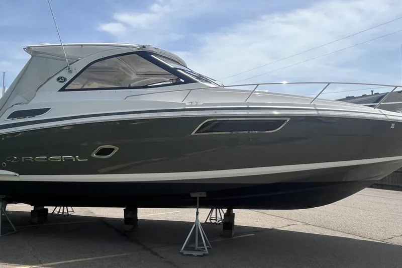 Slide: The Image of 2018 Regal 35 Sport Coupe boat on stands, sleek design under clear sky. - 3