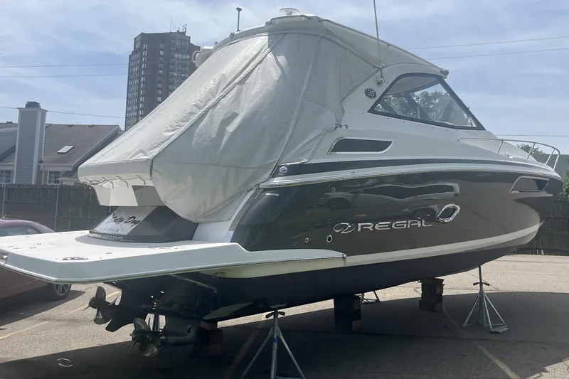 Slide: The Image of 2018 Regal 35 Sport Coupe boat on stands, covered, in a parking area. - 4