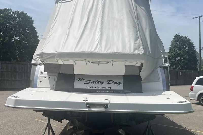 Slide: The Image of 2018 Regal 35 Sport Coupe boat with cover, named "The Salty Dog," in a parking area. - 5