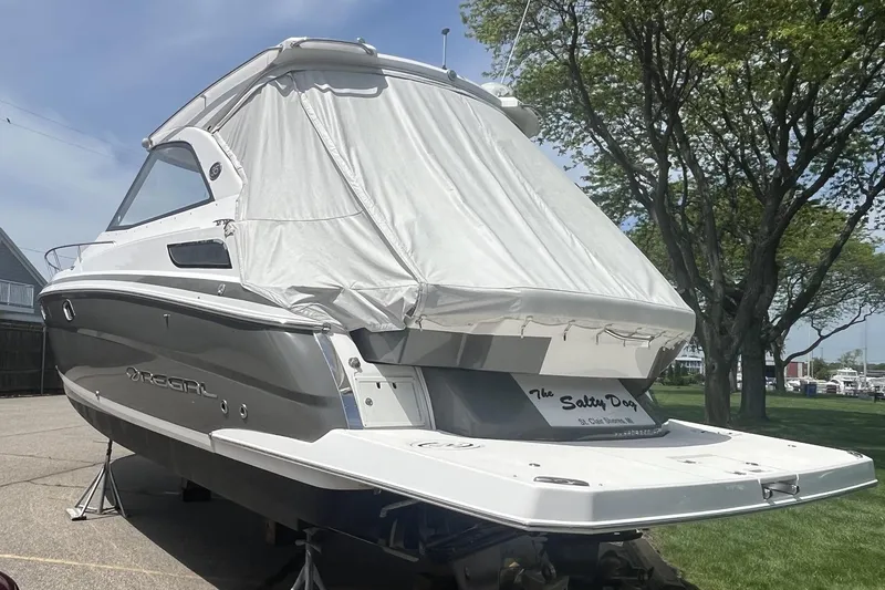 Slide: The Image of 2018 Regal 35 Sport Coupe boat covered, parked on land near trees. - 6