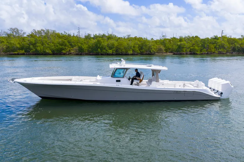 Slide: The Image of 2027 HCB 53 Suenos boat cruising on calm water with lush greenery in the background. - 1
