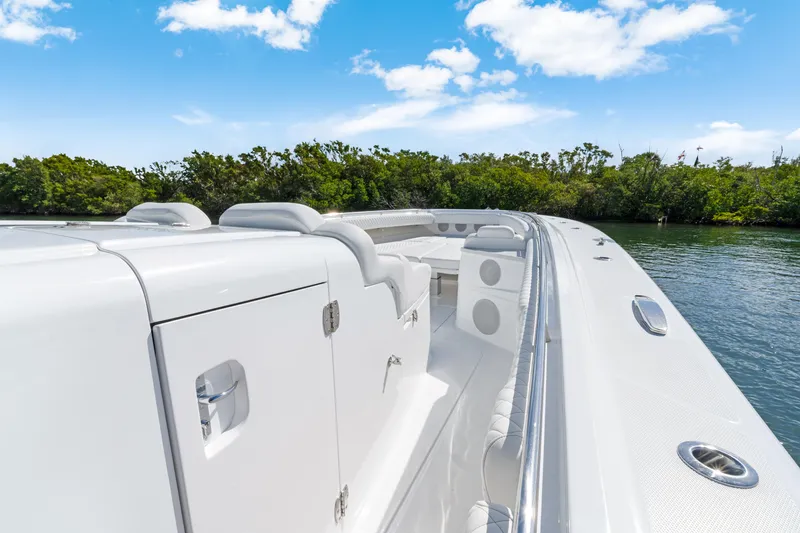 Slide: The Image of 2027 HCB 53 Suenos luxury boat on calm water, clear sky, lush greenery. - 13