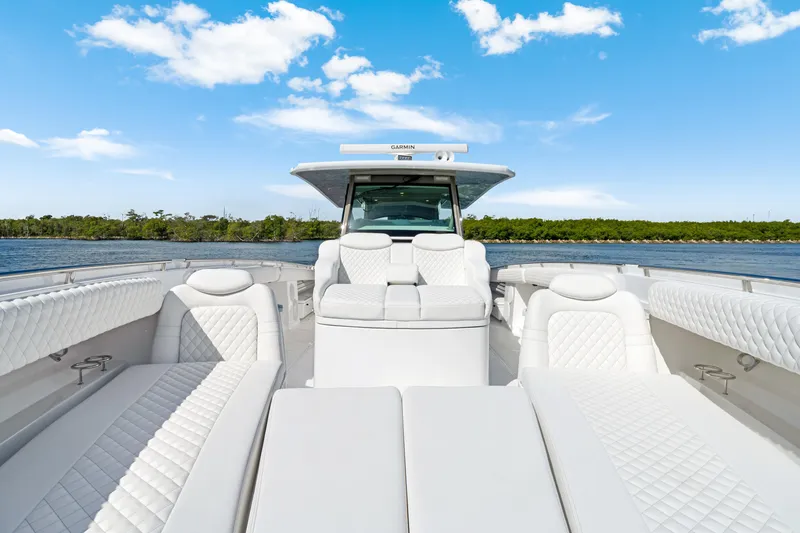 Slide: The Image of 2027 HCB 53 Suenos luxury boat interior with white seating, under a clear blue sky. - 20