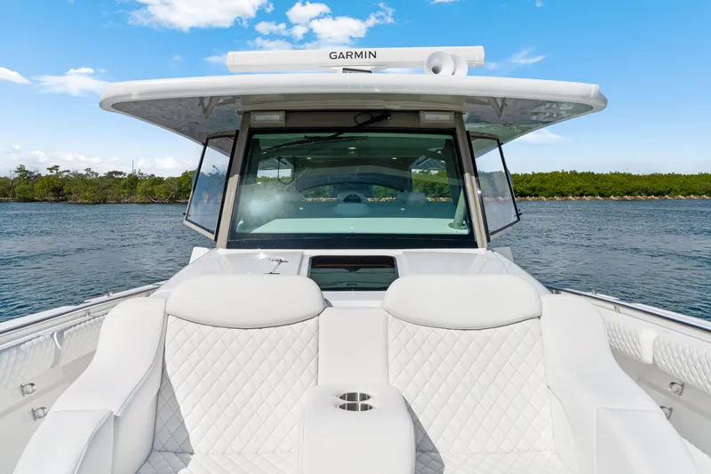 Slide: The Image of Luxury HCB 53 Suenos boat interior with white seating, on a serene water backdrop. - 22