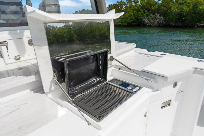 Slide: The Image of Outdoor grill on the 2027 HCB 53 Suenos boat, set against a scenic water backdrop. - 33