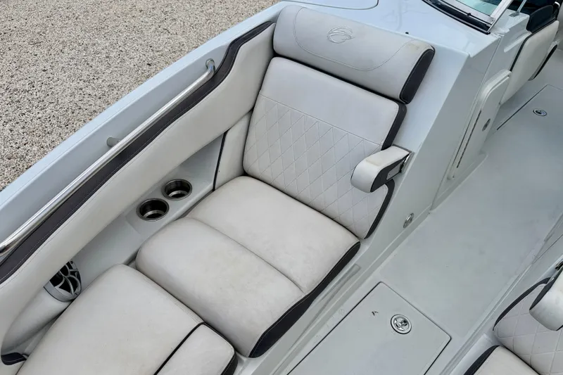 Slide: The Image of 2022 Crownline 260 XSS boat interior with white cushioned seating and cup holders. - 11