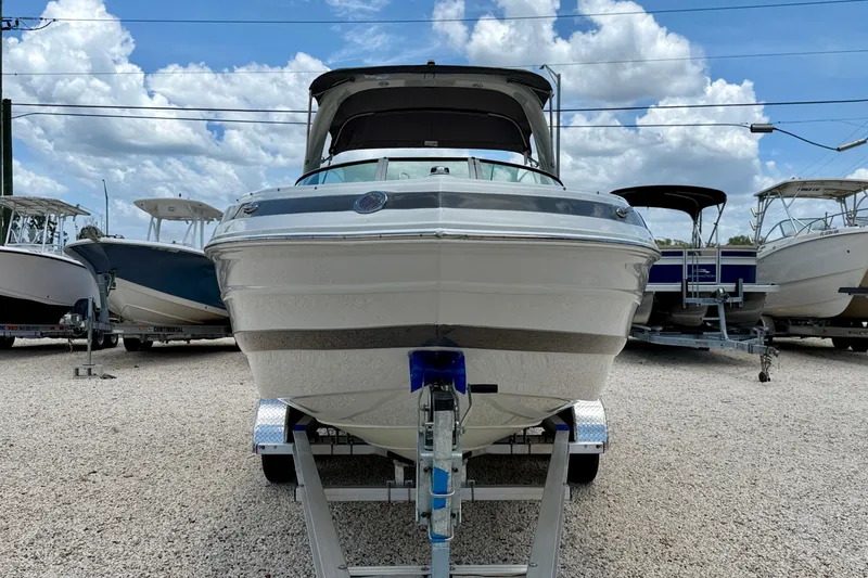 Slide: The Image of 2022 Crownline 260 XSS boat on trailer, displayed outdoors under a cloudy sky. - 2