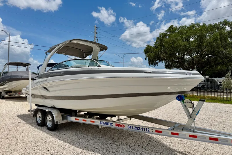 Slide: The Image of 2022 Crownline 260 XSS boat on trailer, parked outdoors under a blue sky. - 3