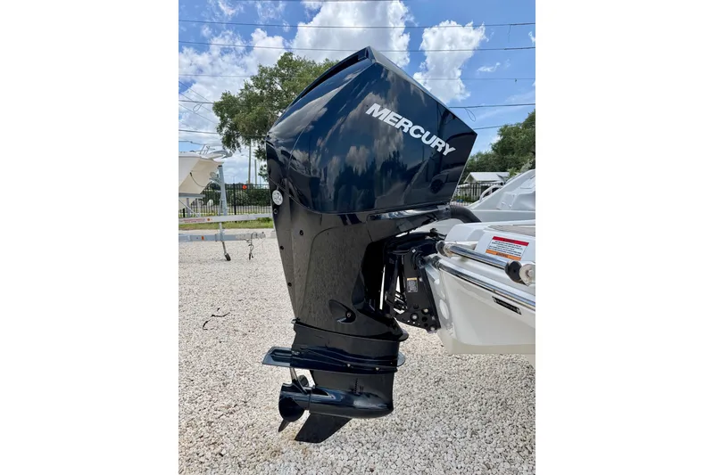 Slide: The Image of 2022 Crownline 260 XSS with Mercury outboard motor, parked on gravel under a blue sky. - 31