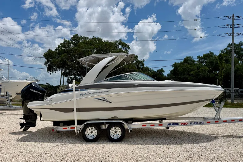 Slide: The Image of 2022 Crownline 260 XSS boat on trailer, parked outdoors under a partly cloudy sky. - 4
