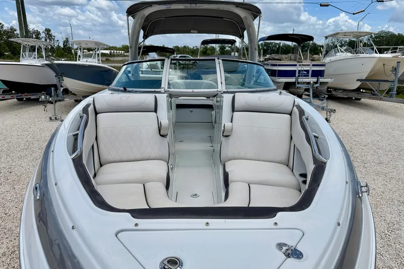 Slide: The Image of 2022 Crownline 260 XSS boat with spacious seating, parked among other boats. - 8
