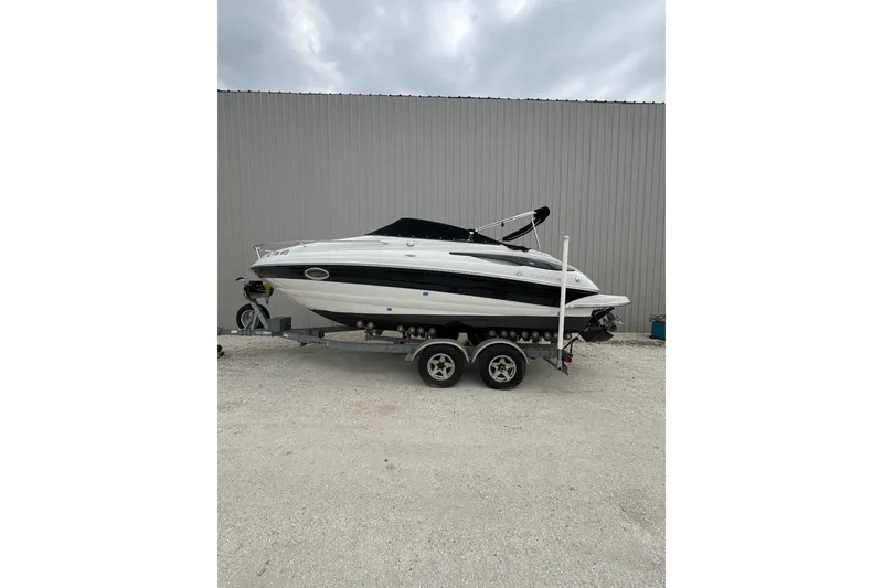 The Image of 2011 Crownline 236 SC boat on trailer, parked outdoors against a metal building. - 0