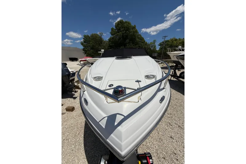 Slide: The Image of 2011 Crownline 236 SC boat, white exterior, parked outdoors under a clear blue sky. - 11