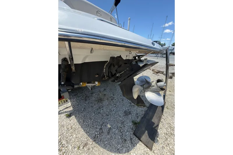 Slide: The Image of 2011 Crownline 236 SC boat stern with propeller, parked on gravel. - 15