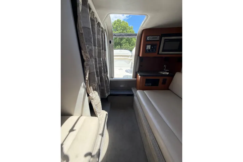 Slide: The Image of Interior of 2011 Crownline 236 SC boat with seating, kitchenette, and window view. - 45