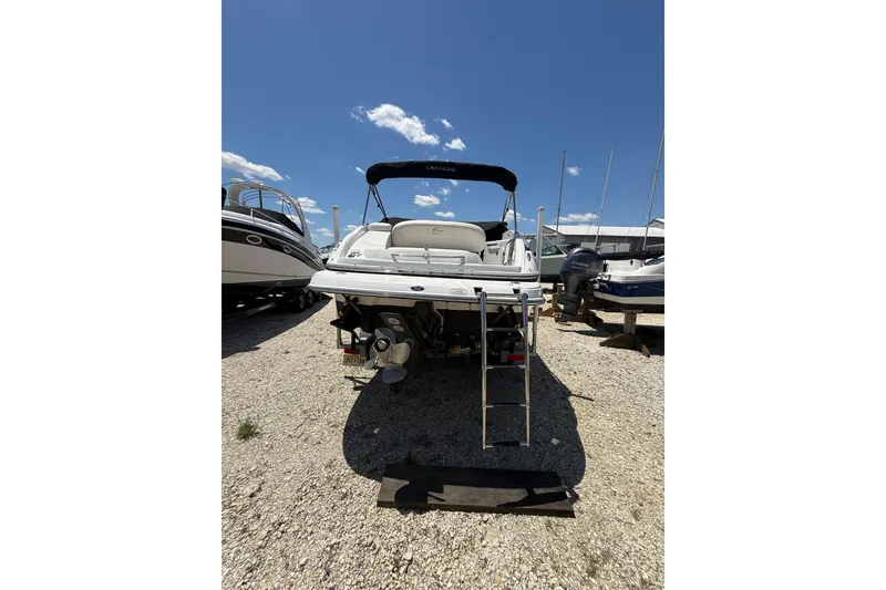 Slide: The Image of 2011 Crownline 236 SC boat with ladder, parked on gravel under clear blue sky. - 8