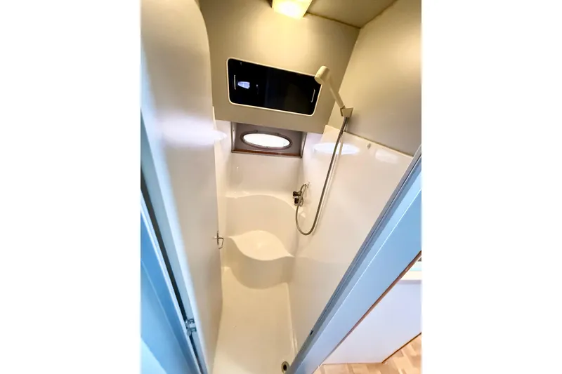 Slide: The Image of 1990 Luhrs 3400 Motor Yacht bathroom with shower, white interior, and porthole window. - 11