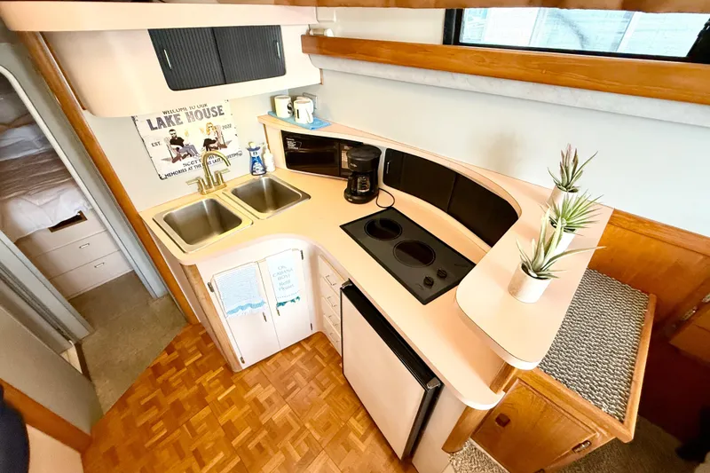 Slide: The Image of 1990 Luhrs 3400 Motor Yacht kitchen with dual sinks, stove, and compact fridge. - 13