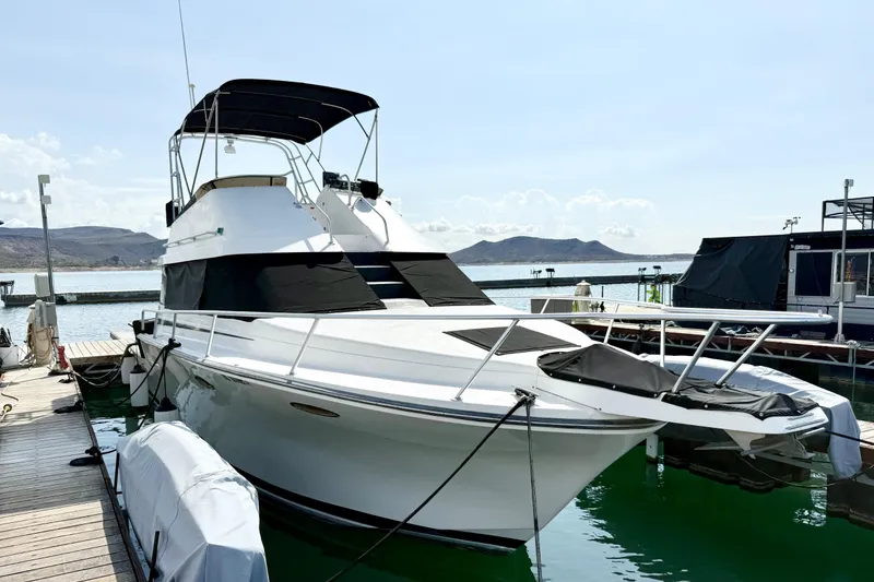 Slide: The Image of 1990 Luhrs 3400 Motor Yacht docked at marina with scenic mountain backdrop. - 5