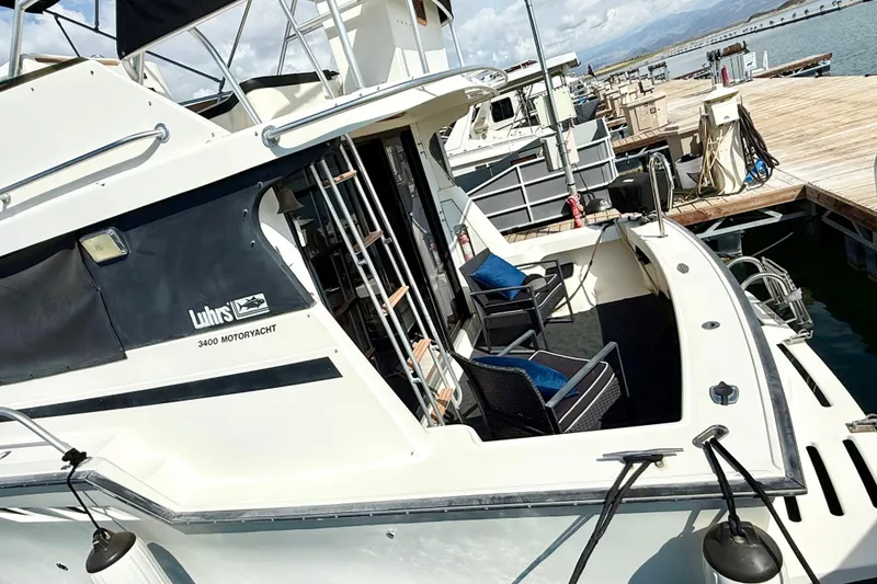Slide: The Image of 1990 Luhrs 3400 Motor Yacht docked, featuring outdoor seating and sleek design. - 6