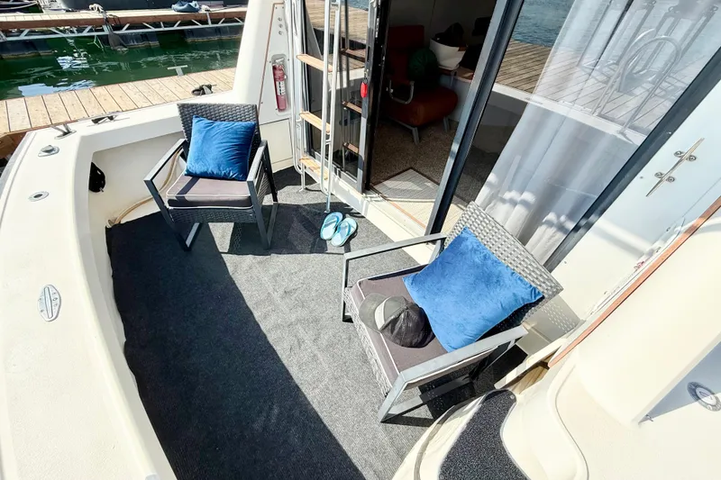Slide: The Image of 1990 Luhrs 3400 Motor Yacht deck with chairs, blue cushions, and dock view. - 7