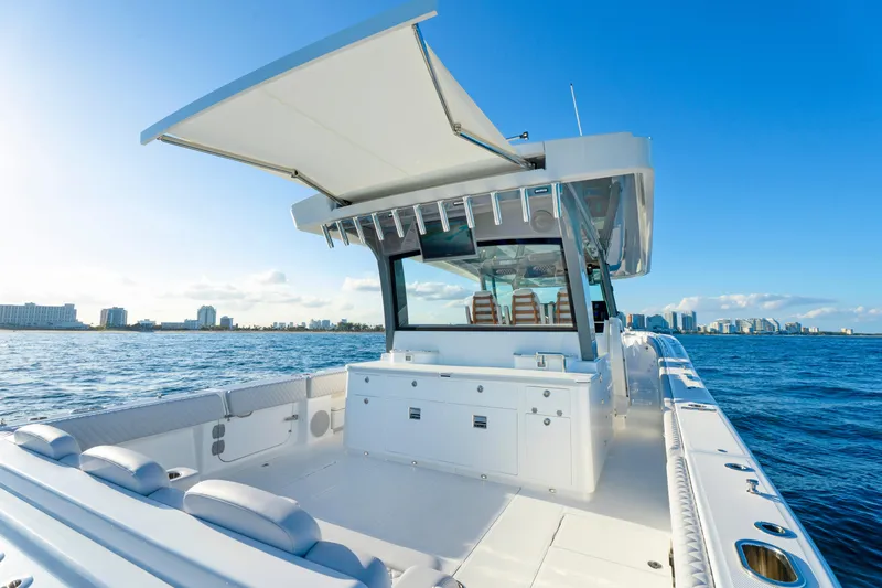 Slide: The Image of 2027 HCB 56 Suenos luxury boat on open water, clear sky, city skyline in background. - 58