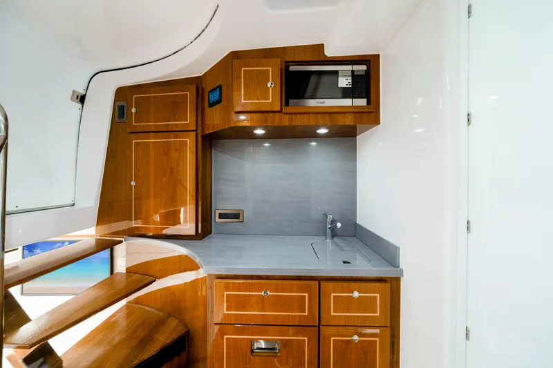 Slide: The Image of Luxurious interior of 2027 HCB 56 Suenos yacht featuring modern kitchenette with wood cabinetry. - 60