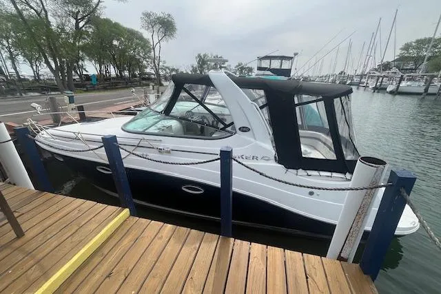 The Image of 2007 Rinker 280 Express Cruiser docked at a marina with trees and boats in the background. - 0