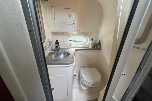 Slide: The Image of 2007 Rinker 280 Express Cruiser bathroom with sink, toilet, and porthole window. - 14