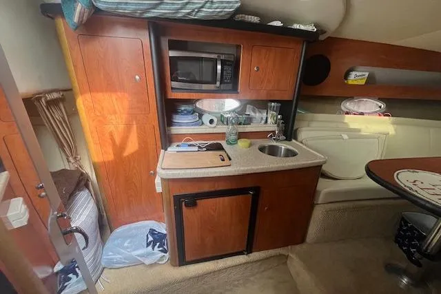 Slide: The Image of 2007 Rinker 280 Express Cruiser interior with kitchenette, microwave, sink, and storage cabinets. - 18