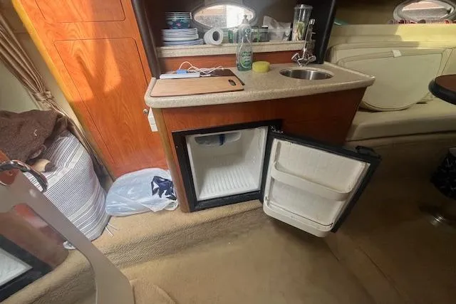 Slide: The Image of 2007 Rinker 280 Express Cruiser interior with kitchenette, open mini-fridge, and sink. - 19
