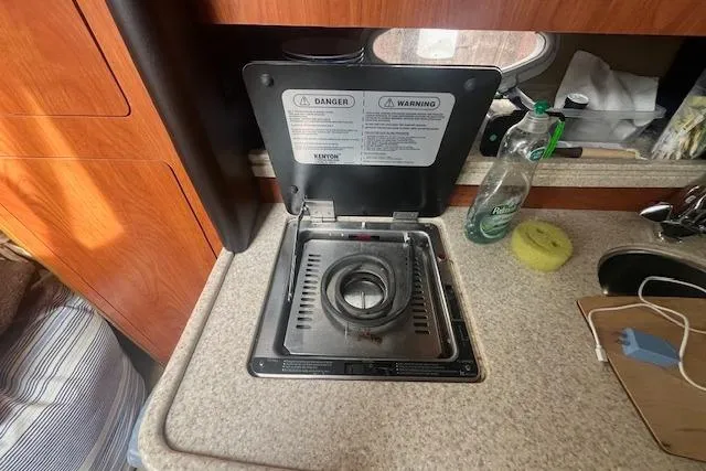Slide: The Image of 2007 Rinker 280 Express Cruiser interior with stove, countertop, and cleaning supplies. - 20