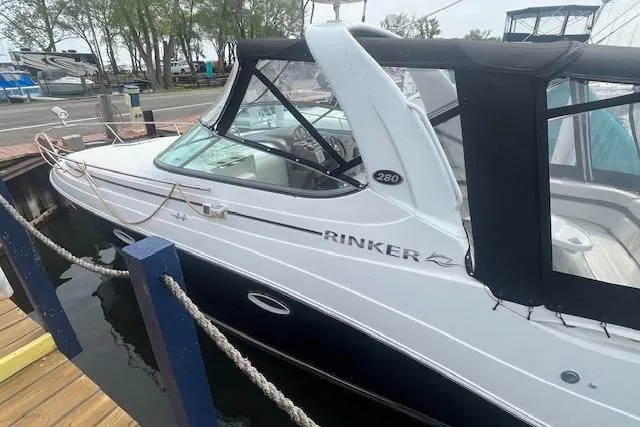Slide: The Image of 2007 Rinker 280 Express Cruiser docked, featuring sleek design and black canopy. - 4