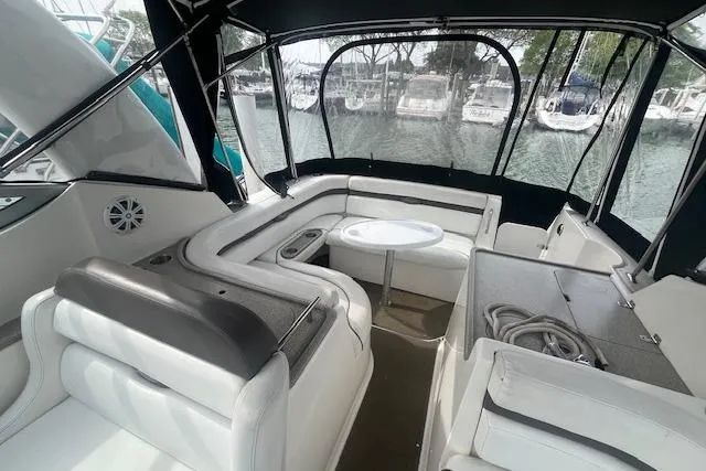 Slide: The Image of 2007 Rinker 280 Express Cruiser interior with seating and table, docked at marina. - 8