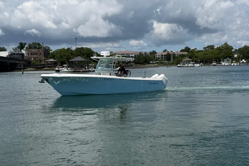 Slide: The Image of 2021 Sailfish 290 CC boat cruising on a calm waterway under a cloudy sky. - 10