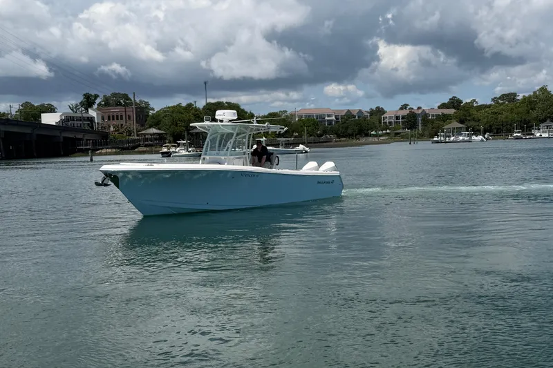 Slide: The Image of 2021 Sailfish 290 CC boat cruising on a calm river under cloudy skies. - 11